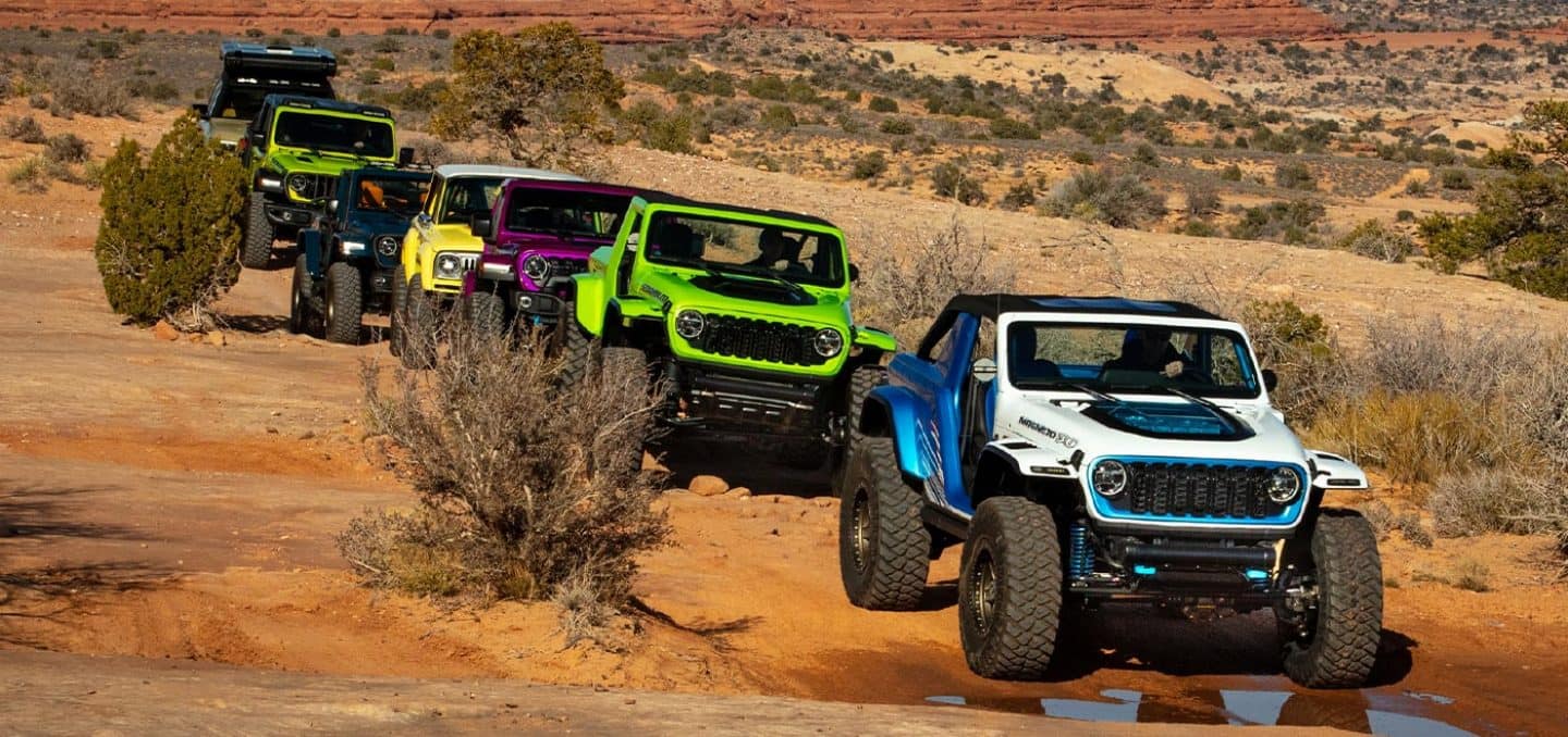 Display A caravan of seven Jeep Brand Concept vehicles being driven through the desert.