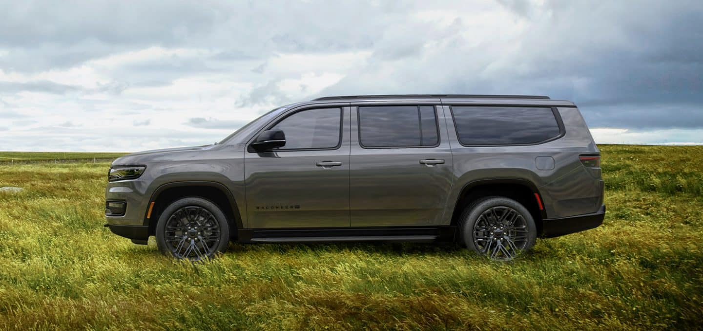 Display A side profile of the 2023 Wagoneer L Obsidian, parked in an open field.