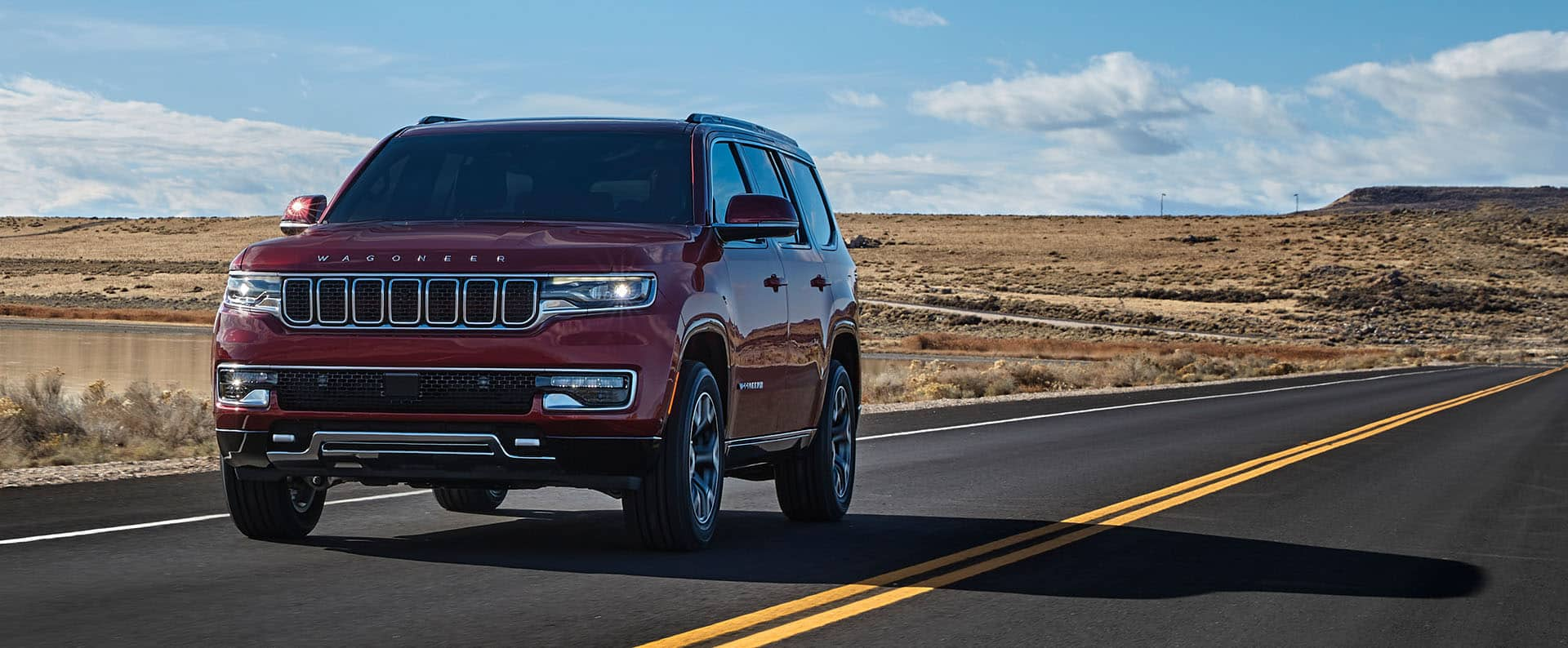 The 2023 Wagoneer Series III being driven on an open road past a desert landscape.