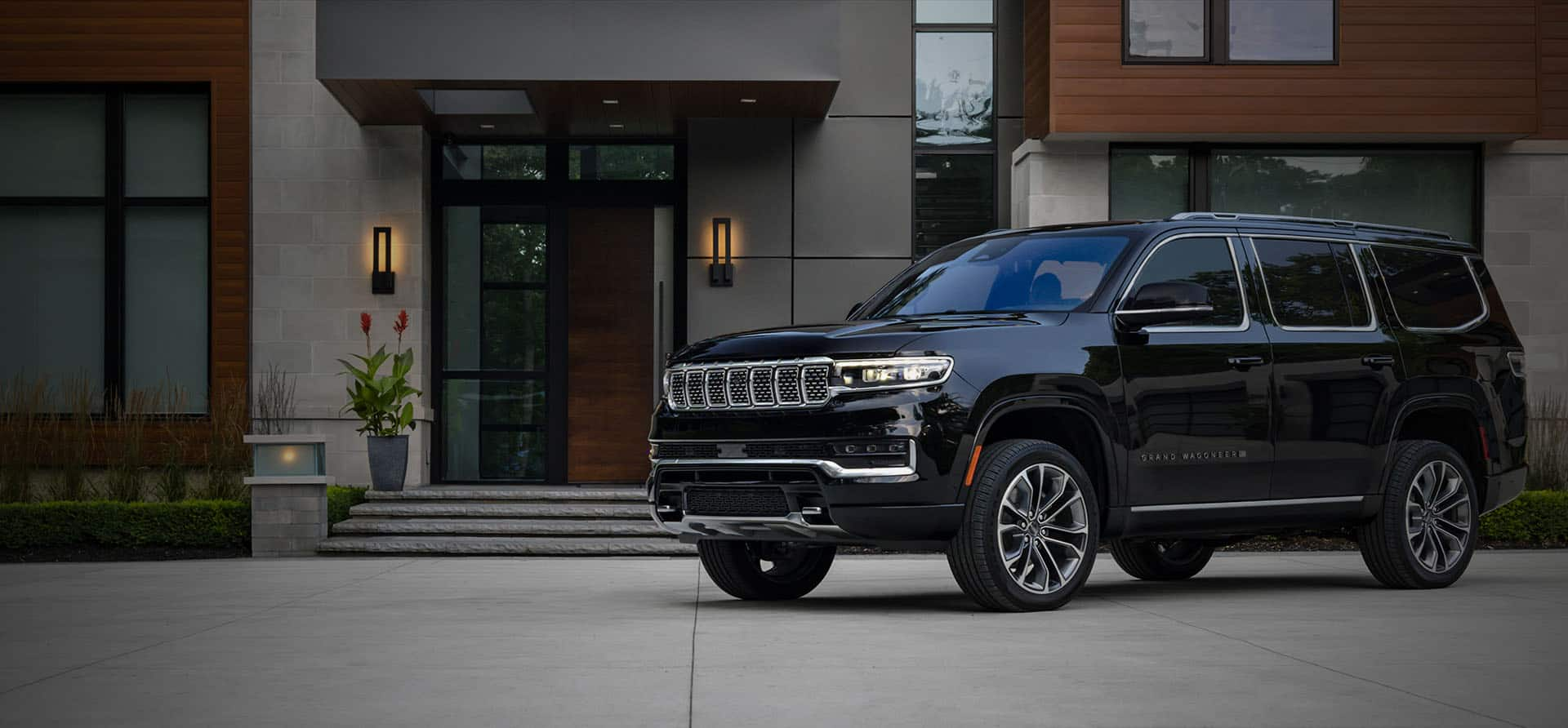 A black 2023 Grand Wagoneer Series III parked in front of a luxury apartment complex at night. The J.D. Power award. Number 1 Driver Appeal among Large Premium SUVs in 2022 by J.D. Power.