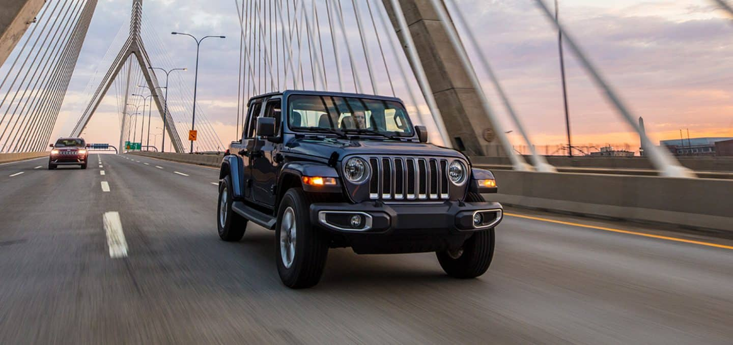 Display The 2023 Jeep Wrangler Overland being driven over a bridge.