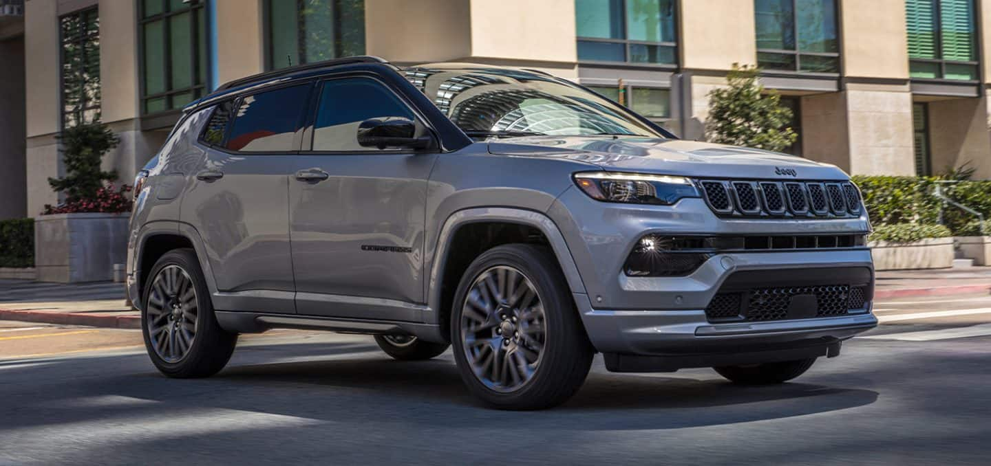 Display A 2024 Jeep Compass High Altitude being driven through an intersection on a city street.